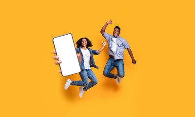 Black couple showing white empty smartphone screen and jumping