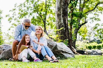Naklejka na ściany i meble Happy family reading book relax in weekend holiday lifestyle park outdoor nature background.