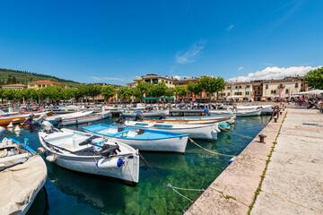 Fototapeta na wymiar Small port of Lake Garda (Lago di Garda) with many boats moored, and cityscape of Garda, famous tourist resort in Verona province, Veneto, Italy, southern Europe.