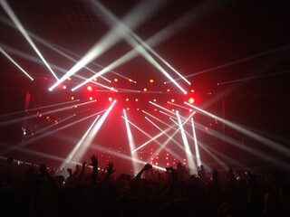 White strobe lights at a gig. A crowd of fans raising their hands at a live concert. A bunch of...