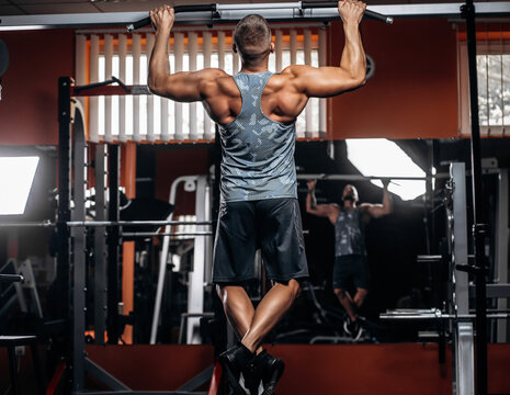 Power muscular bodybuilder guy doing pullups in gym. Fitness man pumping up lats muscles. Fitness and bodybuilding training health lifestyle concept - Powered by Adobe