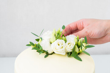 Obraz na płótnie Canvas The process of decorating the cake with flowers, close-up. Sweet cake with floral decor