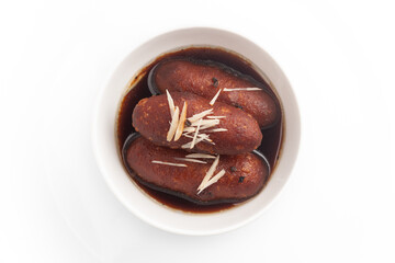 Close-up of Indian Bangali traditional sweet dish Pitha or Peetha ( Roshopuli ) made from red sweet potato, garnished with chopped almond and dry nuts with cardamom dipped into sugar syrup 