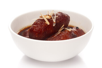 Close-up of Indian Bangali traditional sweet dish Pitha or Peetha ( Roshopuli ) made from red sweet potato, garnished with chopped almond and dry nuts with cardamom dipped into sugar syrup 
