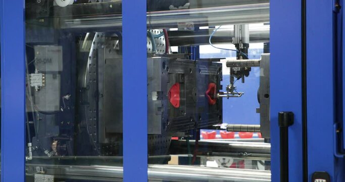 View Through Transparent Glass Enclosure Of Injection Molding Machine During Operation. close up