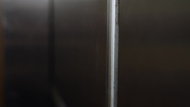 Close up. Side angled shot of automated brushed aluminum elevator doors going from open to closed shut.