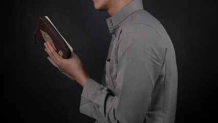 muslim boy reading quran from the side