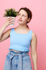 beautiful woman in a blue T-shirt and shorts a flowerpot pink background unaltered