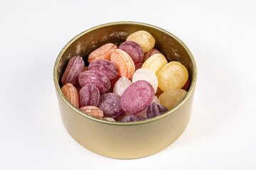 Colored candies in a metal box on a white background. Lollipops and sweets
