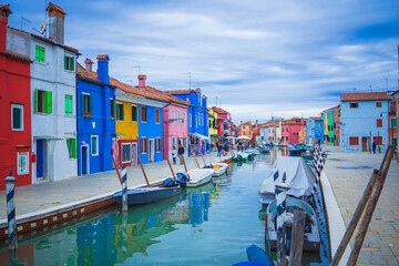 Fototapeta na wymiar View of streets with colorful houses in Burano along canal. Typical tourist place burano island in Venetian lagoon Italy. Beautiful water canals and colorful architecture. Burano Italy 7 october 2021