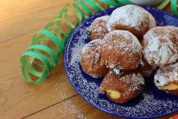 Traditional italian Fritters called Frittelle on a plate with Carnival decorations. Fritters with raisins