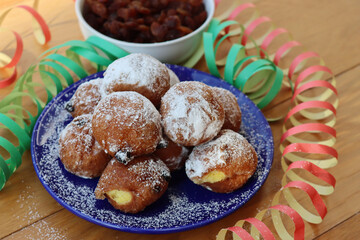 Traditional italian Fritters called Frittelle on a plate with Carnival decorations. Fritters with raisins