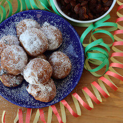Traditional italian Fritters called Frittelle on a plate with Carnival decorations. Fritters with raisins