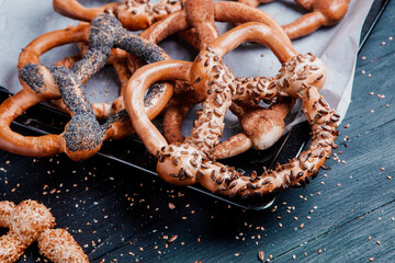 Fresh prepared homemade soft pretzels. Different types of baked bagels with seeds on a black background.