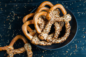 Fresh prepared homemade soft pretzels. Different types of baked bagels with seeds on a black background.