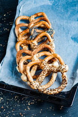 Fresh prepared homemade soft pretzels. Different types of baked bagels with seeds on a black background.