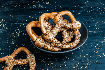 Fresh prepared homemade soft pretzels. Different types of baked bagels with seeds on a black background.