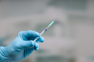 Close up of doctor's hand in medical gloves with a pulled up syringe ready for vaccination in front...
