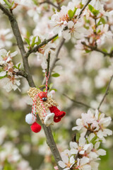 Red and white beautiful martisor hanging on the branches of the blooming tree.