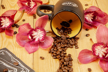 Obraz na płótnie Canvas Scattered coffee beans. a cup of black coffee, espresso. orchid flowers. Traditional hospitality and care. (the inscription on the 