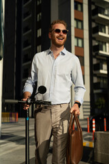 Fototapeta na wymiar Young stylish businessman with e-scooter. Portrait of handsome man outdoors.