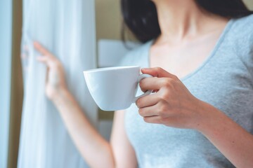 Asian woman drinking coffee in the morning in bed.