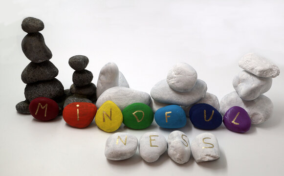 Mindfulness written on painted stones in rainbow / chakra colors. Balancing stones