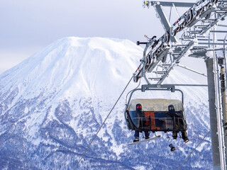 Chairlift with a snowy volcano in background (Niseko, Hokkaido, Japan)