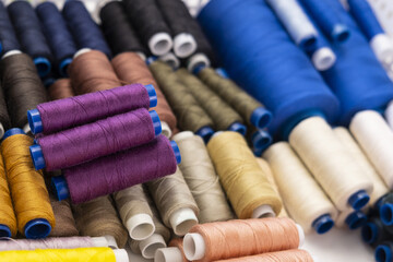 Multi-colored sewing threads laid out in a row. Bright background