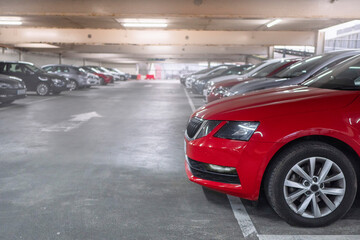 Row of cars in a car park or dealership. Selective focus. Red color car in foreground. Busy parking lot of a shopping mall. Parking prices and vehicle density in town issue. Soft cinematic look