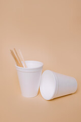 Plastic cups and wooden sticks on background