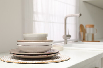 Stack if clean dishes on countertop near sink in kitchen