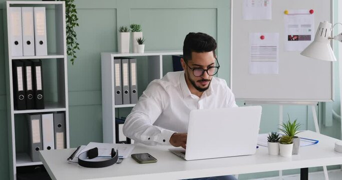 Businessman using laptop while doing paperwork at office