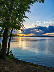 Sunset over a pond with trees in the foreground, forest on the opposite Bank. Russia. Udmurtia.