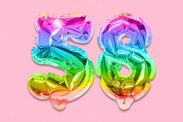 Rainbow foil balloon number, digit fifty eight on a pink background. Birthday greeting card with inscription 58. Top view. Numerical digit. Celebration event, template.