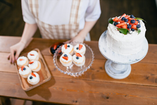 Pastry Chef Confectioner Young Caucasian Woman Decorate Cake On Kitchen Table. Cakes Cupcakes And Sweet Dessert Top Overhead View