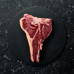 The T-bone or porterhouse steak of beef. Aged steak. Top view. On a black stone background.