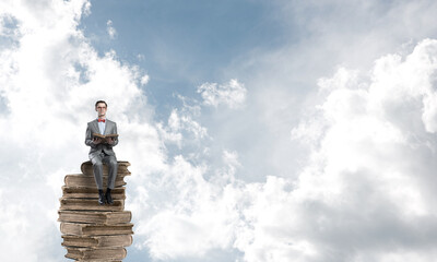 Young businessman or student floating in blue sky and studying the science