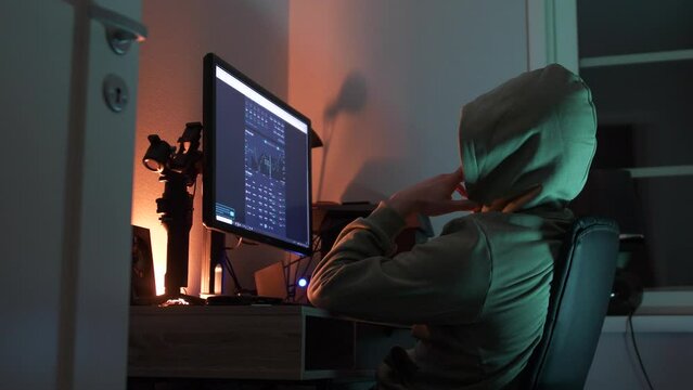 Daytrader nerd follows Crypto currency market live on computer screen in dark room, low angle side view dolly shot