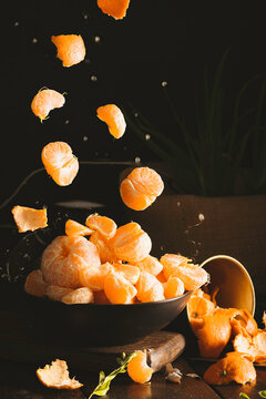 Juicy tangerines falling on dark backgorund