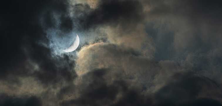 Photograph of New Moon in the cloudy gloomy night sky.