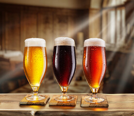 Cooled glass of beer with condensate on the wooden table. Blurred pub at the background.