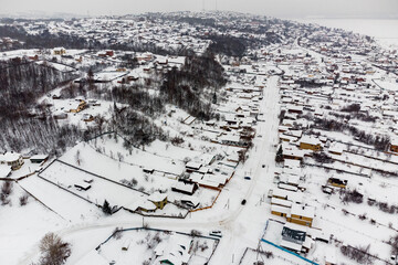 Fototapeta na wymiar Aerial view of fenced areas with houses in snow-covered village on winter day after snowfall