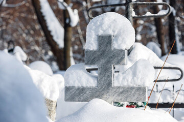 Stone orthodox crucifixion in snowdrift in cemetery