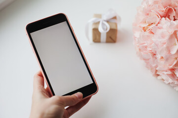 Valentines day, Mobile phone in pink case near pink hydrangea flower and small gift box with ribbon. Surprise for Valentine's Day, sending romantic love message to a loved one on mobile phone.