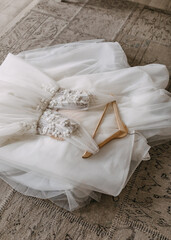 Handmade wedding dress with flower and crystals embroidery, thrown on the floor.