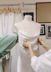 Work process of a wedding dress designer in her studio, sewing bridal dress on a mannequin. 