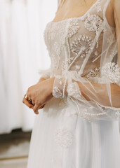 Closeup of a future bride wearing her wedding dress,  manually embroidered, at a wedding showroom.