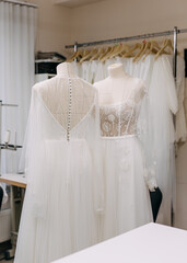 Wedding dresses on mannequins at a fashion designer studio. Fine handmade bohemian wedding gowns with lace embroidery.