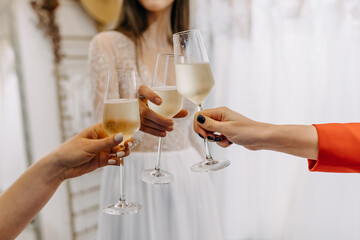 Closeup of a bride and guests raising glasses of champagne at a wedding.